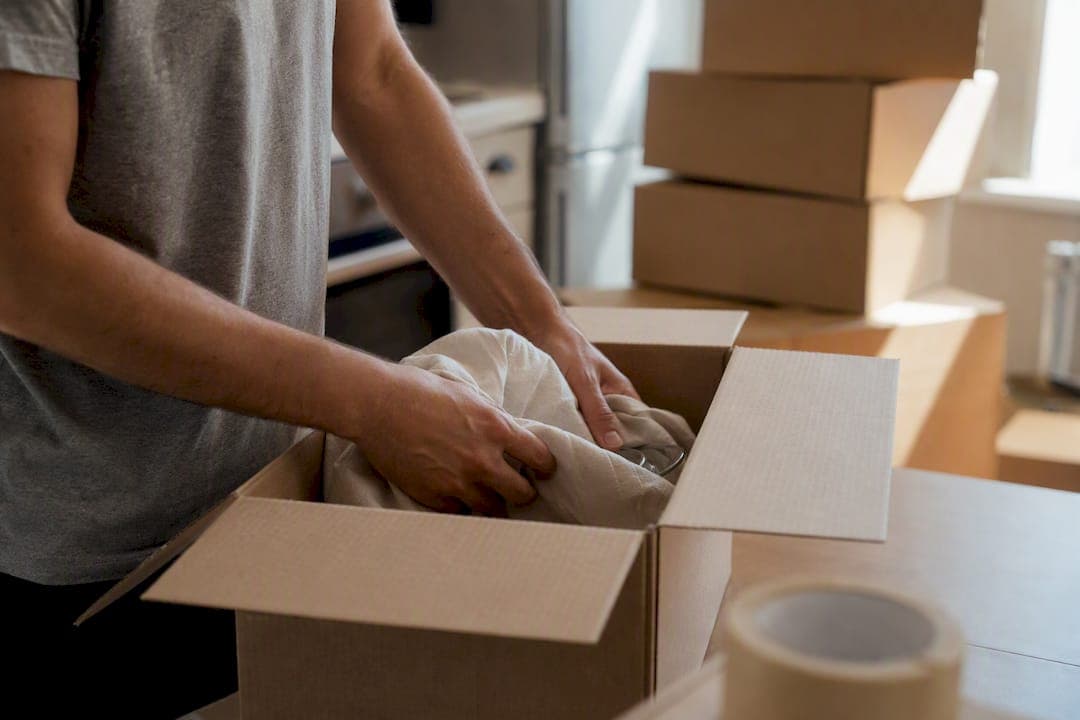 Hands packing moving box in living room